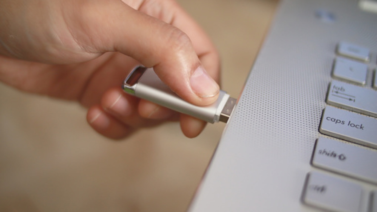 Person inserting plug in flashdisk into usb port in laptop personal computer, data transfer device concept, close up