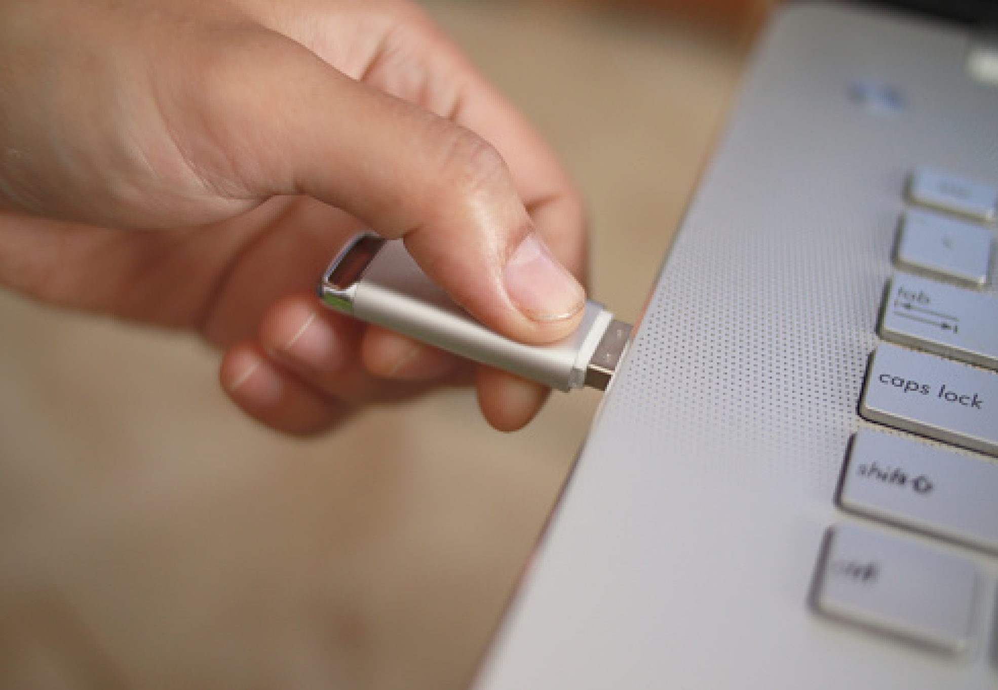 Person inserting plug in flashdisk into usb port in laptop personal computer, data transfer device concept, close up